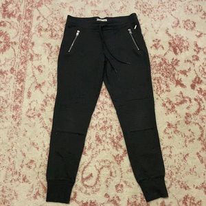 Grey pants with zippers on pockets.